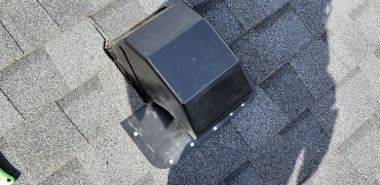 A person wearing a brown work boot stands on a gray shingled roof next to a black roof vent; the persons shadow is visible on the shingles. Dominion Roofing | BRAMPTON | BURLINGTON | ETOBICOKE | MARKHAM | MISSISSAUGA | NORTH YORK | OAKVILLE | RICHMOND HILL | Scarborough | TORONTO | VAUGHAN | dominionroofing.com | Phone Number: 416-789-0601