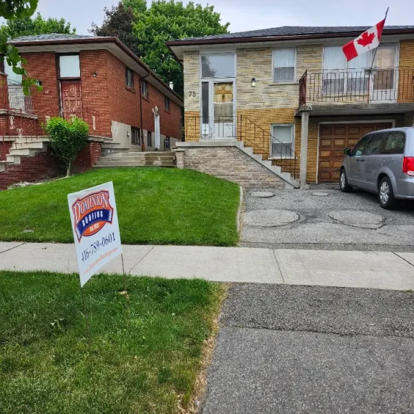 A house with a Canadian flag on the balcony, a car parked in the driveway, and a “Dominion Lending Centres” sign with a phone number on the lawn. The sky is overcast and there are trees and another house nearby. Dominion Roofing | BRAMPTON | BURLINGTON | ETOBICOKE | MARKHAM | MISSISSAUGA | NORTH YORK | OAKVILLE | RICHMOND HILL | Scarborough | TORONTO | VAUGHAN | dominionroofing.com | Phone Number: 416-789-0601
